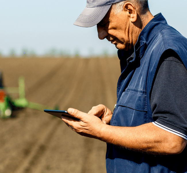 A farmer updates his business Environmental management system using Southpac Plus+ on his smartphone while in the paddock.